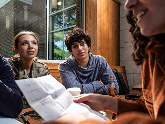 Woman reading a piece of paper with a male and female staring at her