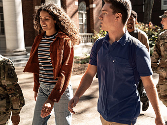 A male and female walking alongside each other on a sunny day