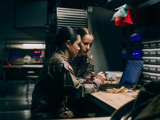 Two female active duty soldiers working together on a laptop
