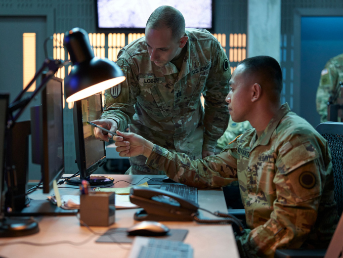 A Cyber Warfare Officer and Soldier pointing at a computer monitor