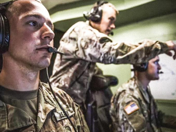 Tres Soldados del Army uniformados con audífonos mirando pantallas enfrente de ellos
