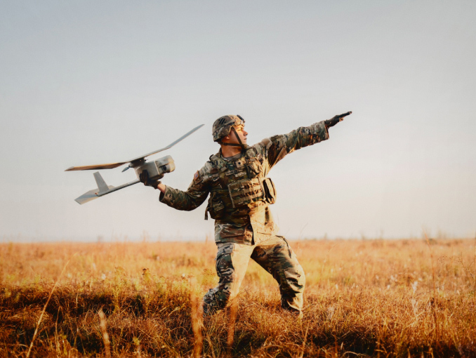 An Army Soldier in combat gear standing outside launching a drone