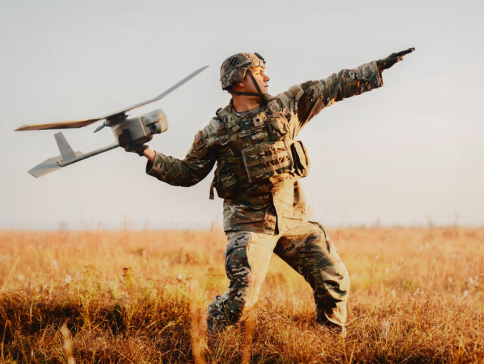 An Army Soldier in combat gear standing outside launching a drone