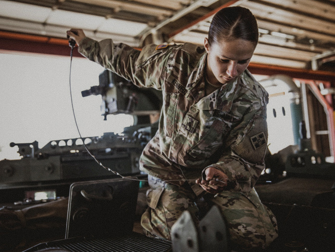 A female Soldier inspecting a mechanical system component