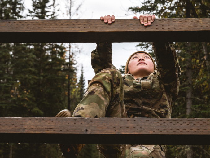 A Soldier climbing a wooden obstacle outside