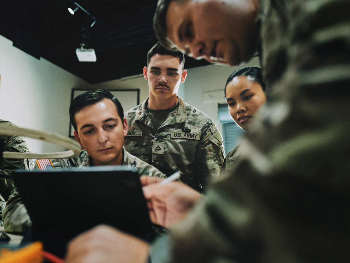 Soldiers in combat uniform looking at a tablet