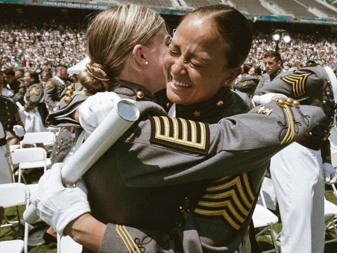 Dos cadetes mujeres de West Point celebrando en una gran ceremonia de graduación 