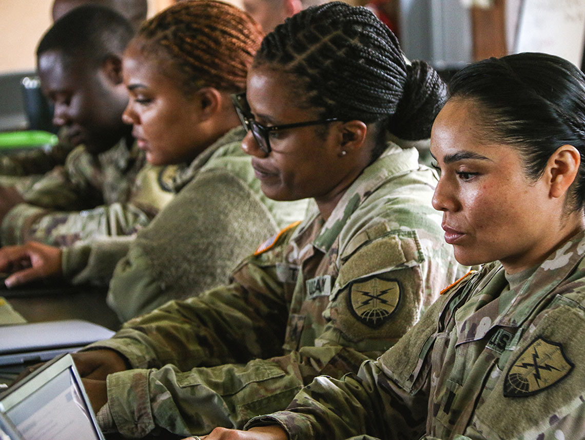 Soldiers siting at a table taking a certification exam