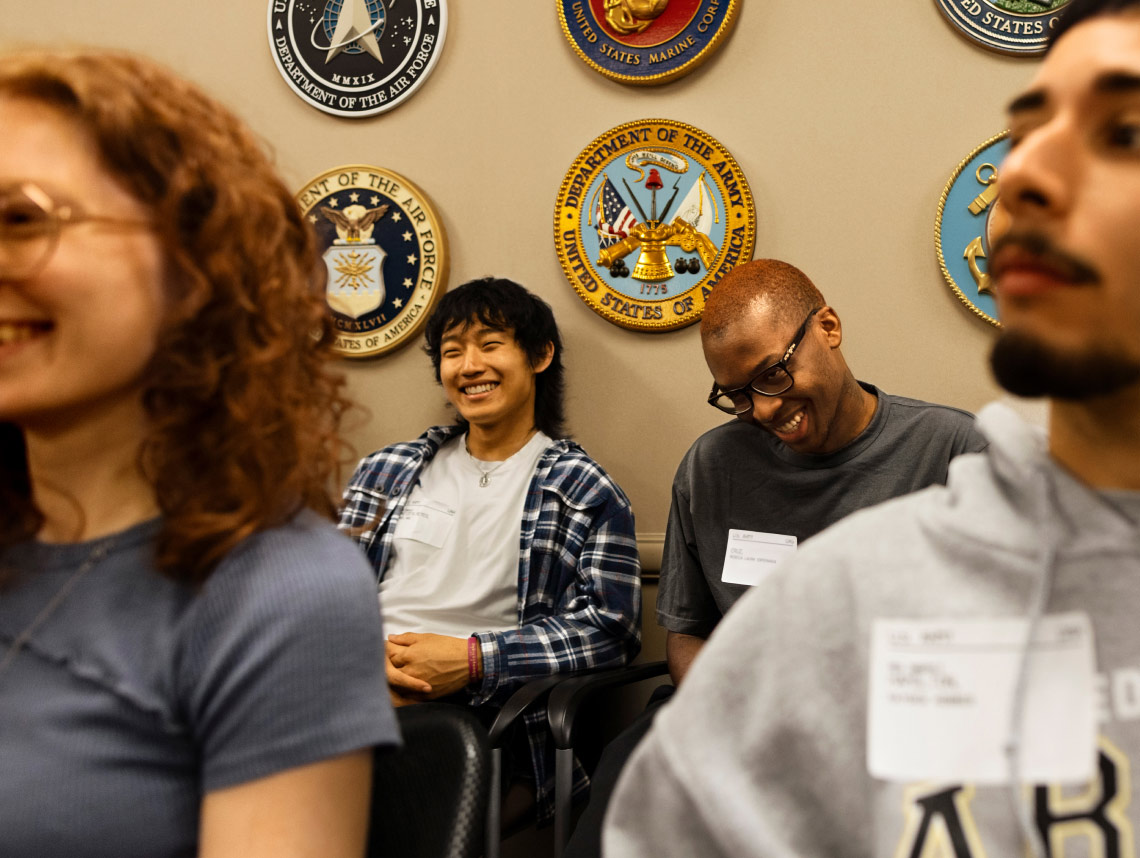 Dos reclutas enlistados sentados y sonriendo en una Military Entrance Processing Station (MEPS)