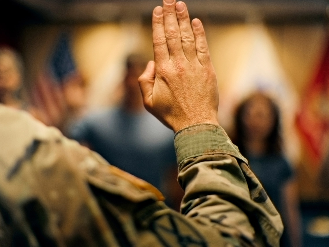 Una mano de piel clara levantada en el aire tomando el Oath of Enlistment