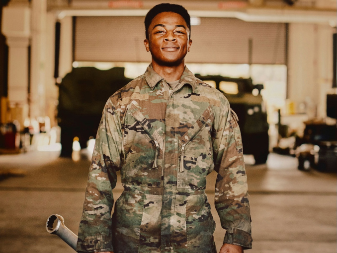 A Soldier holding a large wrench while standing in a garage