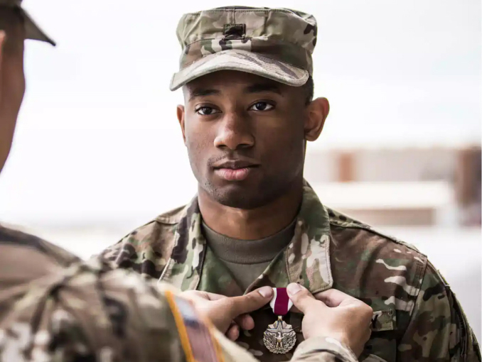 A male Soldier in uniform receives a medal at an outdoor pinning ceremony