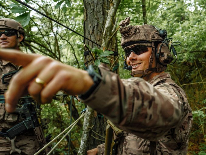 Male Soldier in combat gear smiling and pointing in a forest