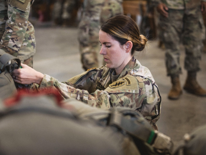 A female Airborne Soldier getting a parachute ready for a jump