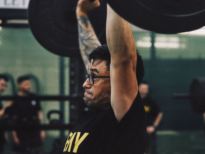 Male Soldier in an Army tee shirt lifting weights in a gym