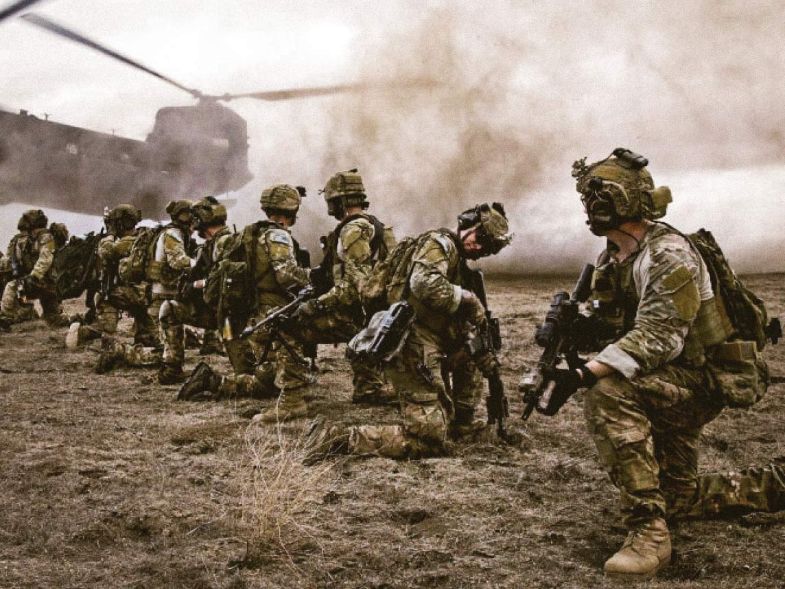 Soldado comandando en el campo, esperando que un helicóptero Chinook despegue