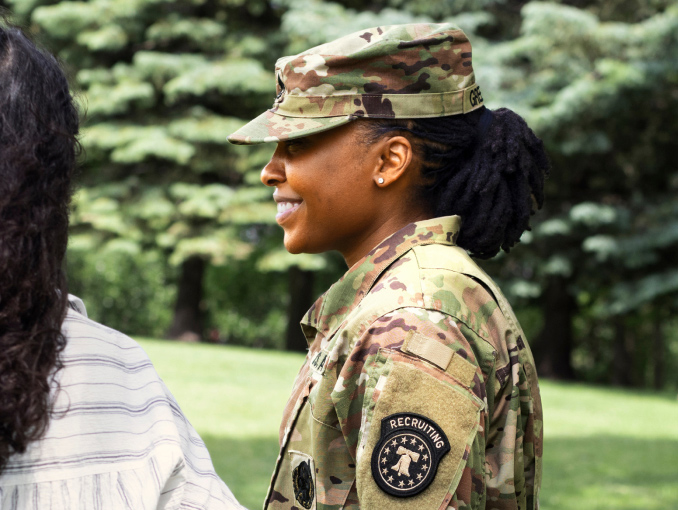 Side view of a female Soldier smiling with landscaping and trees in the background