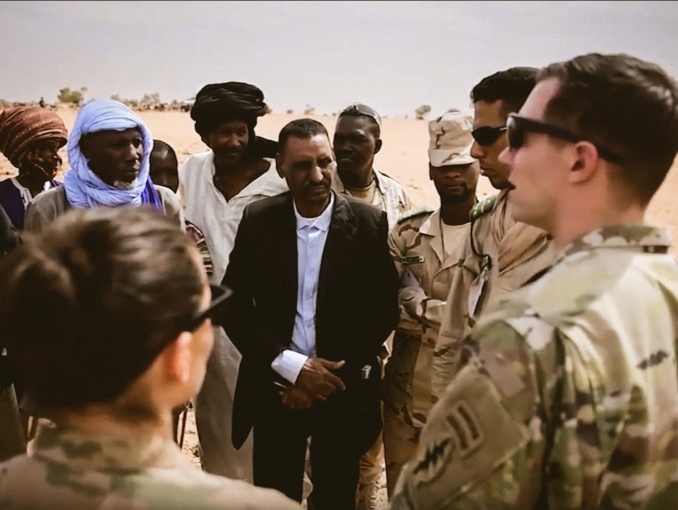 Soldados hablando con civiles locales en un desierto