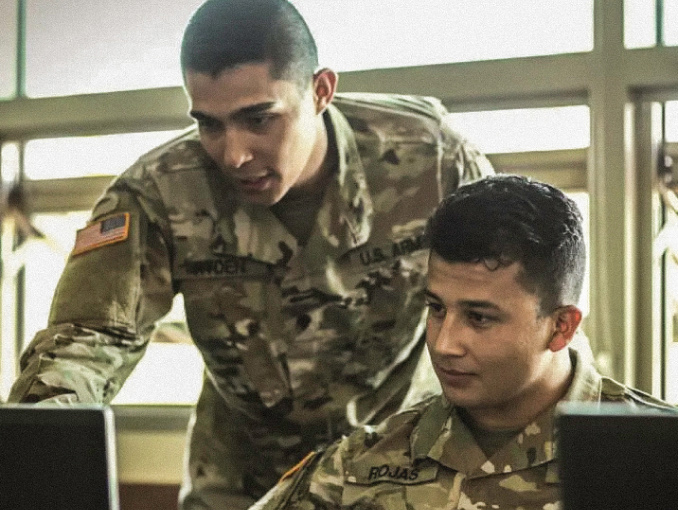 Dos Soldados en un salón de clases mirando una pantalla de computadora
