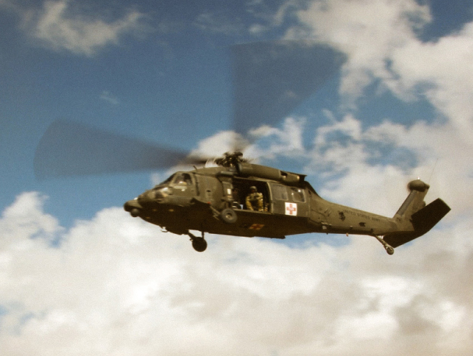 A UH-60 Black Hawk helicopter flying in a desert