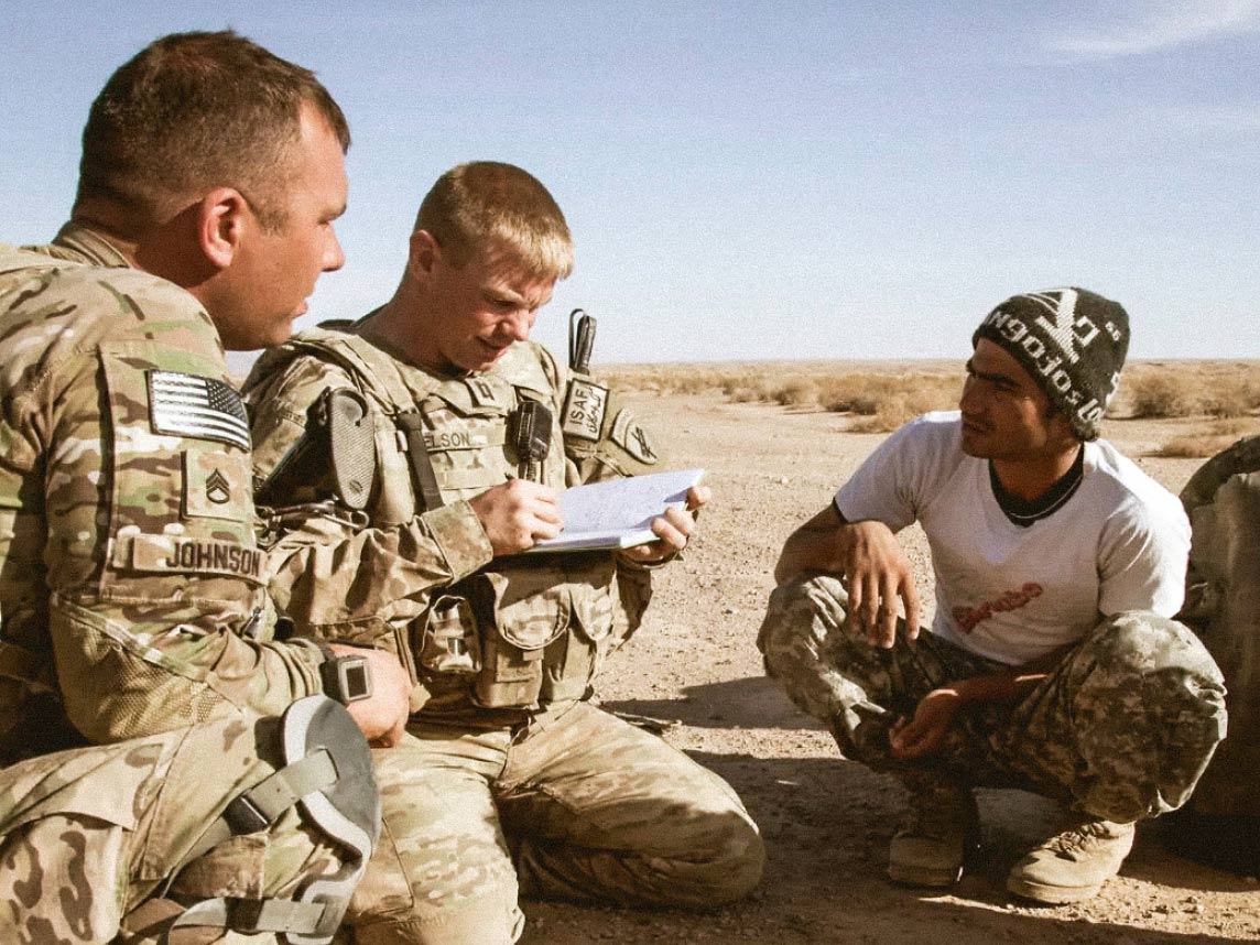 Two Soldiers speaking to local civilians in a desert
