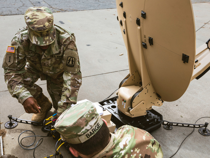 A Warrant Officer working with a Soldier on a portable communications system
