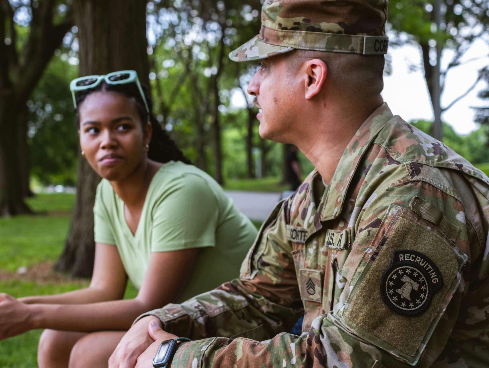 Un reclutador del Army habla con una joven sentada en una banca al aire libre