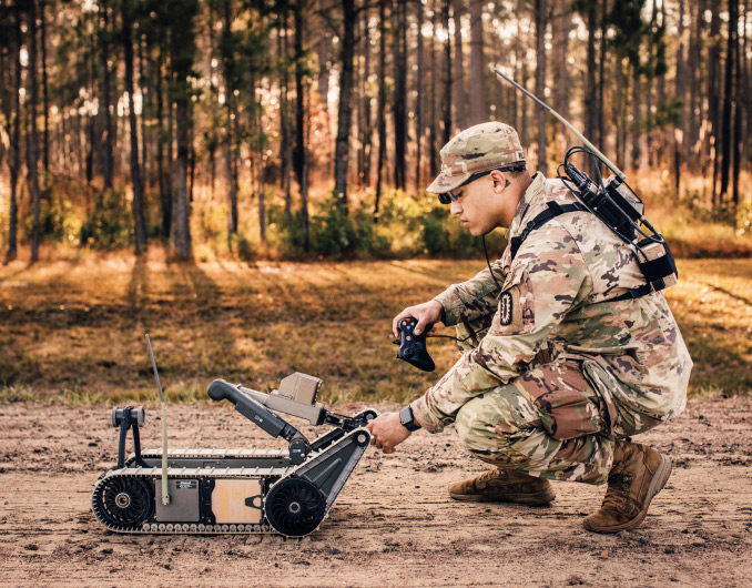 Un Soldado preparándose para operar un robot desactivador de bombas en un camino de tierra