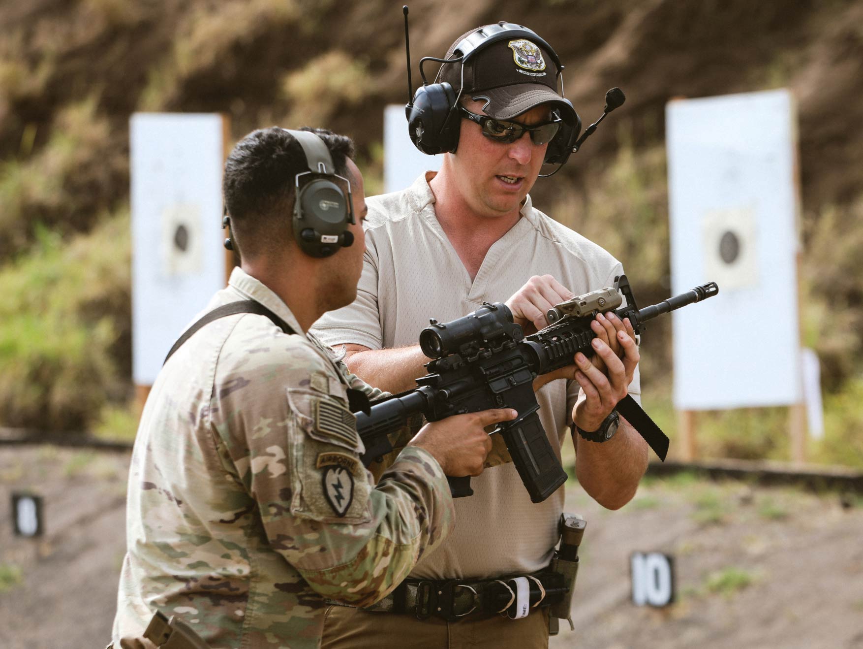 An Army Marksmanship Unit instructor adjusts the rifle a Soldier is holding at a shooting range