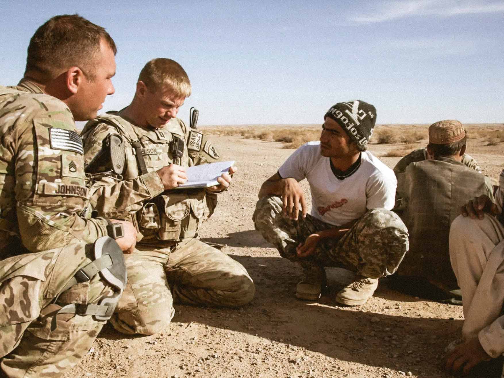 Dos Soldados hablando con civiles locales en un desierto