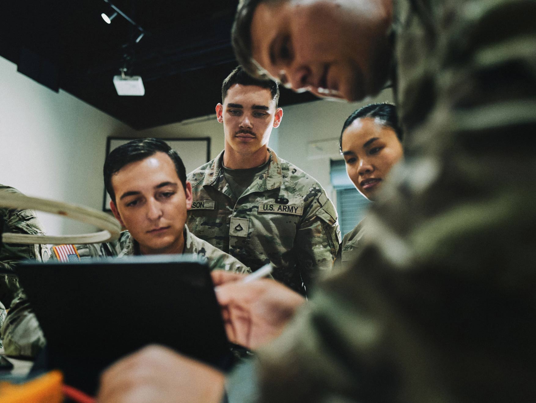 A group of Soldiers in combat uniform looking at a tablet