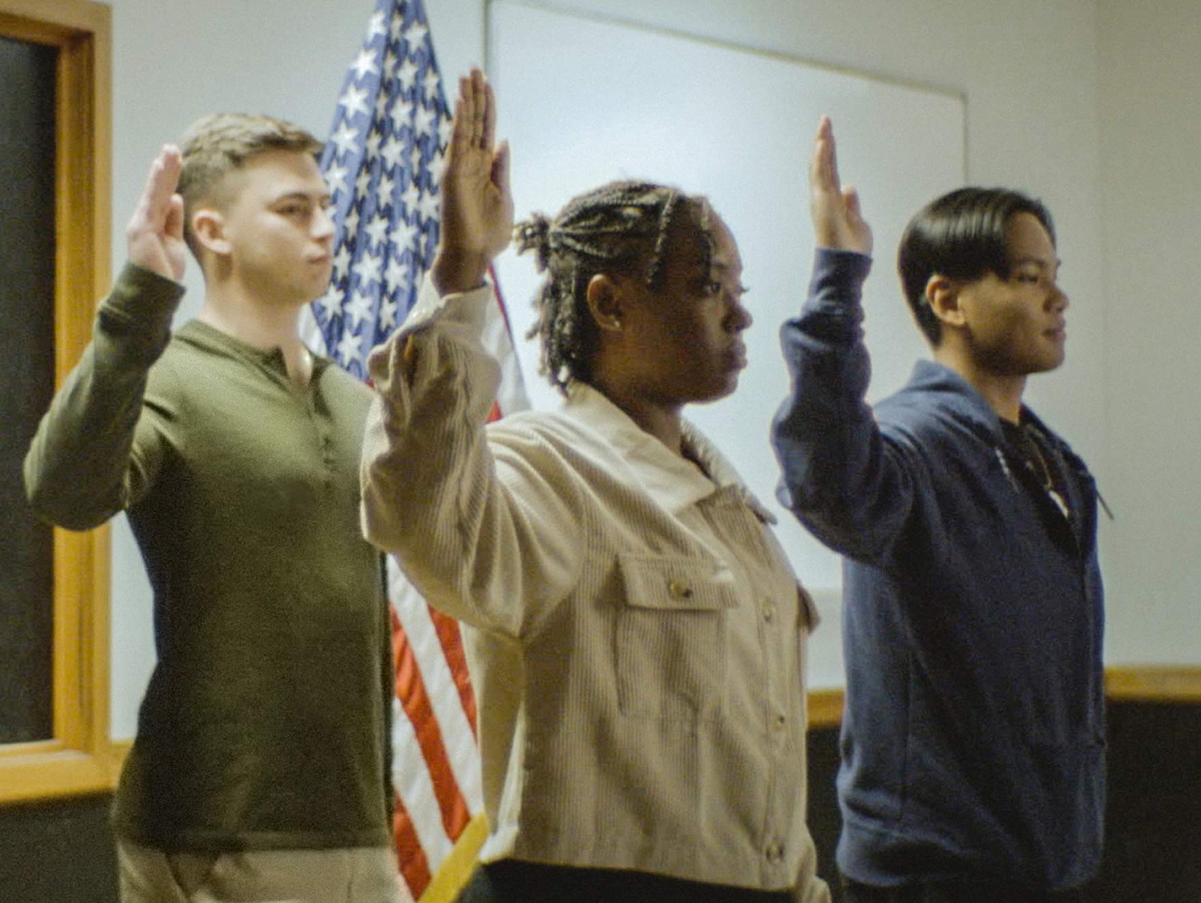 Three recruits raising their arm and taking the Oath of Enlistment