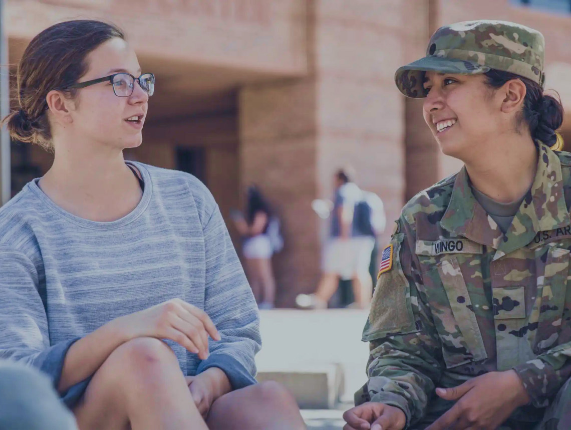 Female ROTC Cadet in combat uniform having a conversation with a student