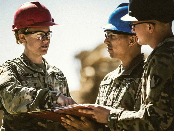 A group of Army engineers discussing plans at a construction site
