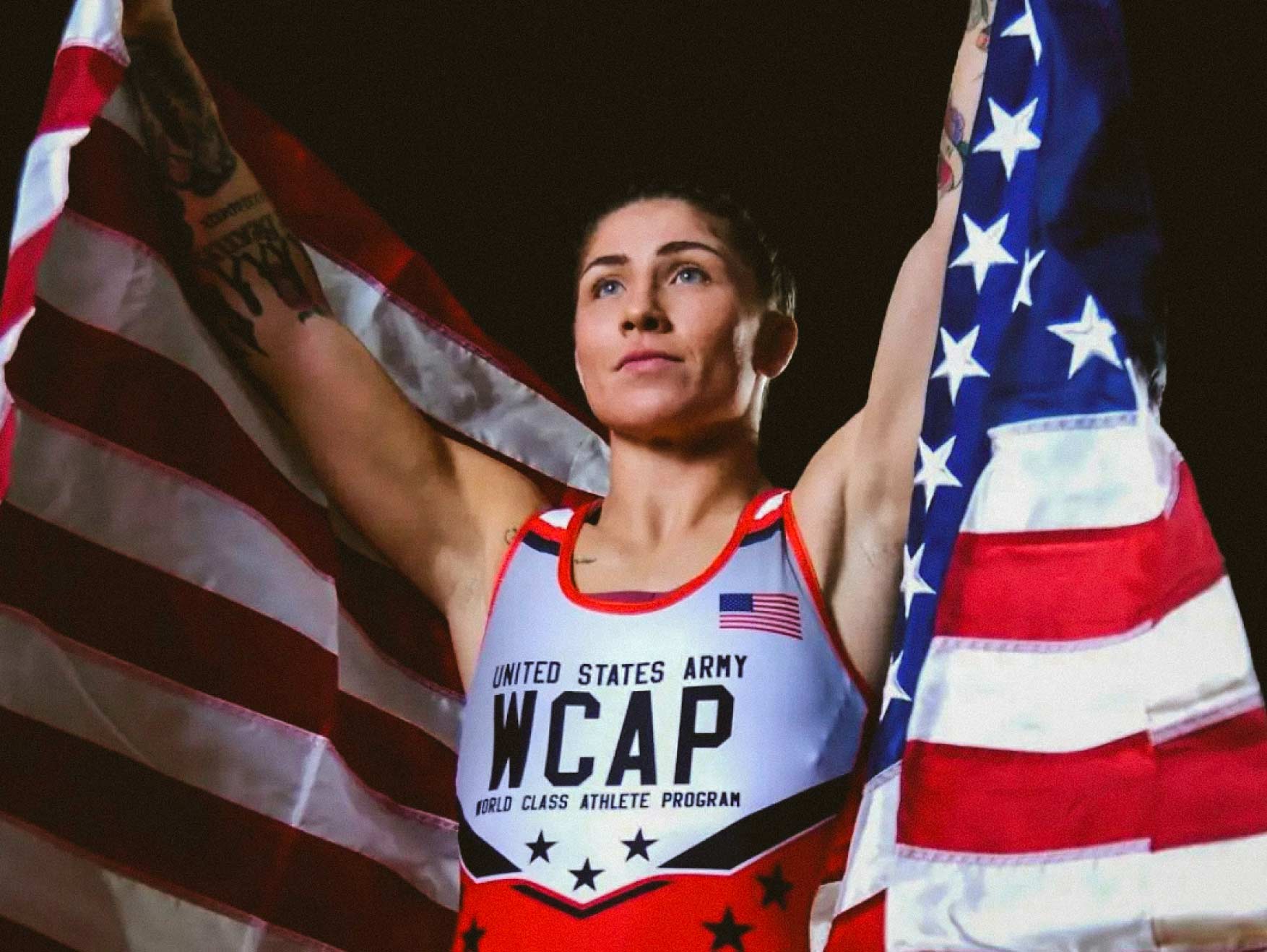 A female World Class Athlete standing and holding a US Flag behind her